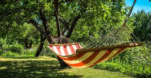 Striped hammock strung between trees in a green garden — hypnotherapy case study of a healer learning to rest